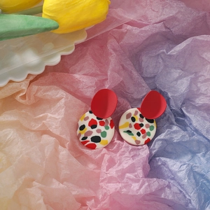 Detail shot of colorful abstract geometric clay earrings on artistic wrinkled paper background