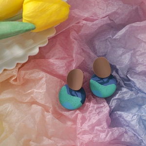 Detail of geometric clay earrings featuring blue and brown marbled textures and matte finish