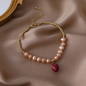 Detailed view of handmade beaded bracelet with pink pearls and a red dried flower pendant