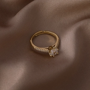 Détail d'une bague dorée avec zircone et monture couronne sur satin brun