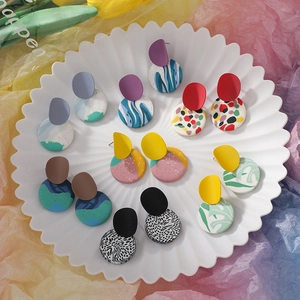 Assorted handmade geometric clay earrings with abstract patterns in a decorative ceramic dish