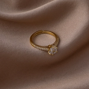 Vue détaillée d'une bague dorée ajustable avec un zircon rond serti dans une monture à six griffes
