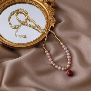 Detail view of handmade pearl necklace with dried rose bud pendant on silk