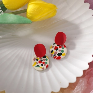 Detail of handmade clay earrings with red and terrazzo circles on a shell tray