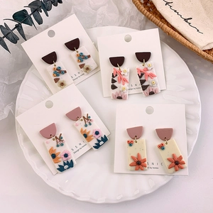 Detailed macro shot of handmade floral clay earrings on display cards with natural decor