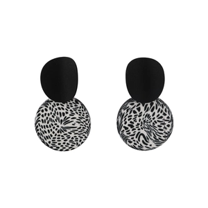 Detail of geometric clay earrings with matte black discs and spotted leopard pattern spheres