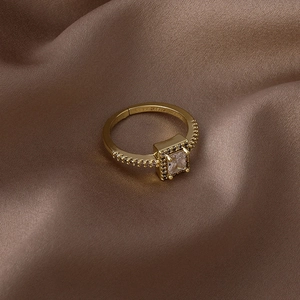 Gros plan d'une bague dorée ajustable avec zircon carré et sertissage à quatre griffes