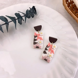 Macro view of handmade floral clay earrings with delicate pink flower motifs and rectangle base