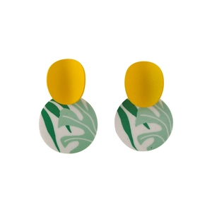 Detail of geometric clay earrings with bright yellow studs and green monstera leaf patterns