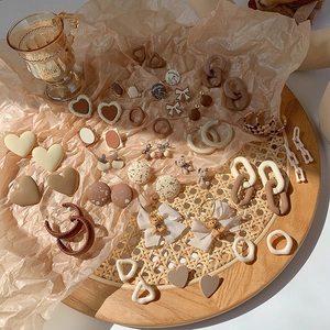 Flat lay of vintage earth tone earrings and hair accessories on a woven wood tray