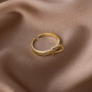 Golden buckle ring with cubic zirconia inlay on elegant brown silk background