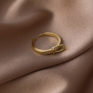 Macro detail of golden belt buckle ring with sparkling zircons on silk background