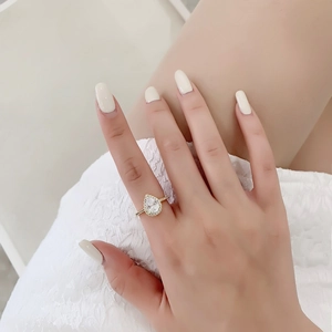 Détail d'une bague dorée élégante avec zircone en forme de poire et serti pavé sur le doigt