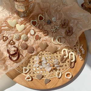 Vintage earth-tone earring set featuring heart shapes and bows on a retro rustic tray