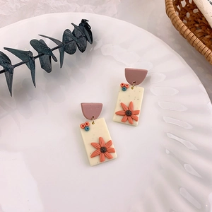 Detail view of handmade floral earrings with sunflower design on white ceramic plate