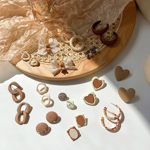 Retro brown earring set featuring heart studs and bow bear accents on art paper