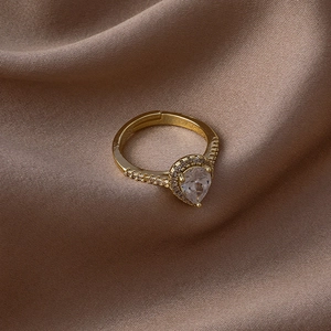 Vue macro d'une bague dorée en zircone poire sur fond de soie marron avec halo scintillant