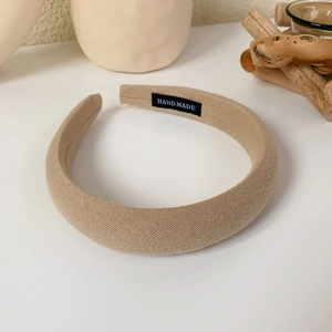 Detail view of khaki sponge headband with handmade label on soft fabric surface