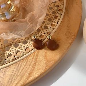 Detail of vintage brown leather textured earrings with a polished gold metallic sphere top