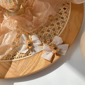 Detail of vintage gold hoop earrings with white organza bows and brown flocking bears