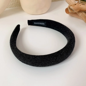 Close-up of thick black sponge headband with handmade label on a clean white desk