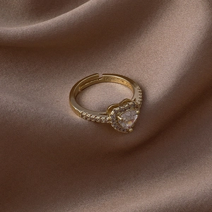 Détail d'une bague dorée réglable avec zircon coeur et cristaux pavés sur soie marron