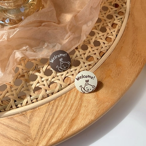 Detail view of round bear badges in coffee and beige on a cozy woven wooden tray