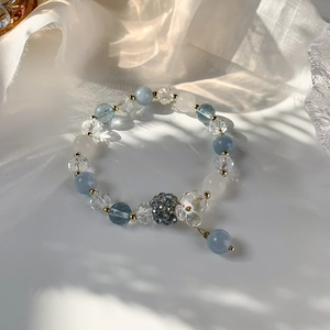 Détail du bracelet perlé avec cristaux bleus, breloque fleur et accents dorés