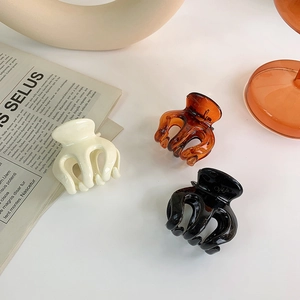 Three-piece set of small glossy resin hair claws in cream white, amber, and black