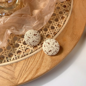 Detailed macro view of ivory round resin studs with brown splatter spots on rattan tray