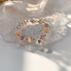 Gros plan d'un bracelet en perles avec pierres pêche et charm fleur en nacre