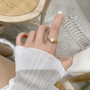 Gros plan d'une bague croisée plaquée or avec pavé de zircons portée à la main
