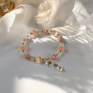 Détail d'un bracelet en cristal avec fleurs de coquillage sur du tissu satiné blanc