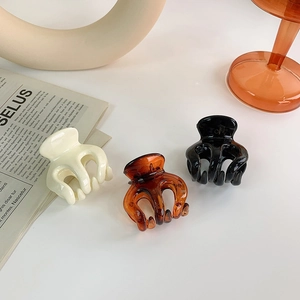 Close-up of three glossy resin claw clips in cream, amber, and black for high ponytails