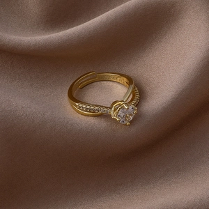 Détail d'une bague dorée ajustable avec zircon rond sur un tissu en satin de soie marron