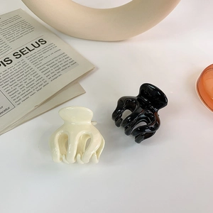 Detail of cream and black octopus-shaped hair claws with high-gloss mirror finish
