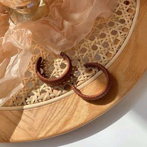 Detail of dark brown leather wrapped hoop earrings on a woven tray display