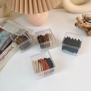 Detailed macro view of multi-color elastic hair ties stored in a clear square organizer box