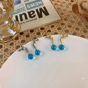 Detail view of faucet-shaped earrings with blue crystal drops on white ceramic plate