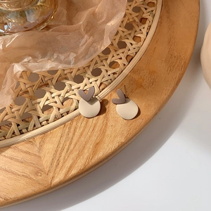 Detail of vintage matte brown heart and beige circle stud earrings on rattan tray