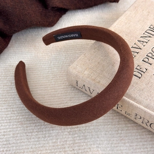 Gros plan sur la texture du serre-tête rembourré marron avec étiquette HANDMADE
