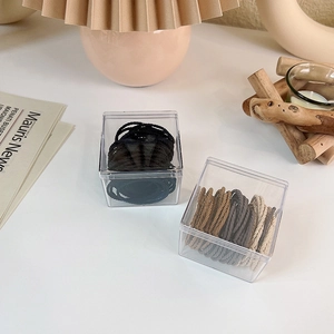 Detail view of 50 elastic hair ties in neutral tones stored in clear acrylic boxes