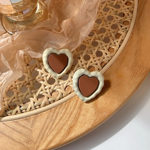 Detailed macro view of vintage heart-shaped earrings in brown and cream resin on a tray