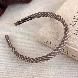 Gros plan sur un serre-tête en tissu écossais marron avec une étiquette faite main