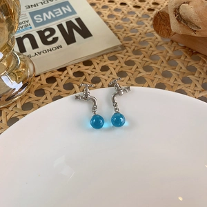 Detail of creative silver faucet earrings featuring translucent blue crystal balls