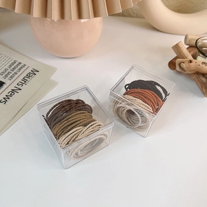Close-up of elastic hair ties in neutral earth tones stored in clear acrylic boxes
