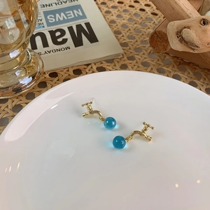 Detailed shot of golden faucet earrings with a translucent blue crystal ball pendant
