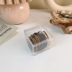 Close-up of elastic earth-tone hair ties in a transparent square storage container
