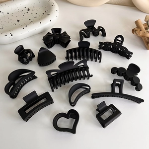 Collection de pinces à cheveux noir mat aux formes variées sur un fond minimaliste