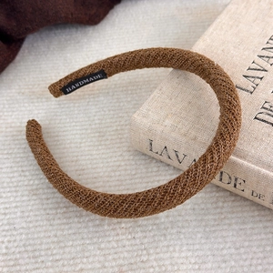 Détail du serre-tête en tricot marron café avec étiquette faite main sur tissu blanc